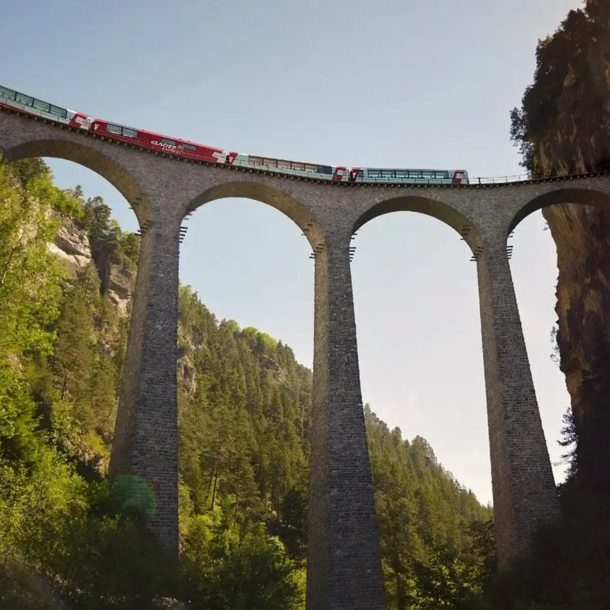 O trem panorâmico Glacier Express viaja pelos Alpes suíços, passando por túneis e sobre pontes majestosas