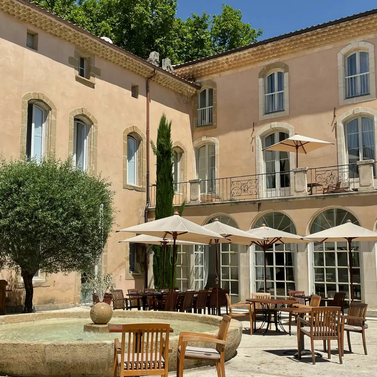 Hotel ou pousada com arquitetura tradicional da Provence, na França, cercados por natureza em dia ensolarado.