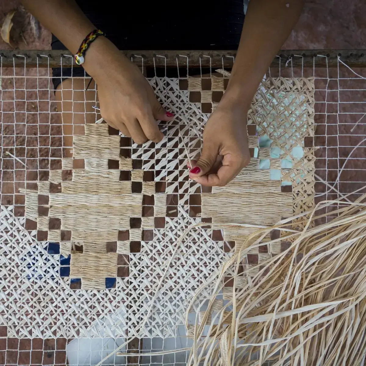 Artesã alagoana fazendo peça com palha entrelaçada