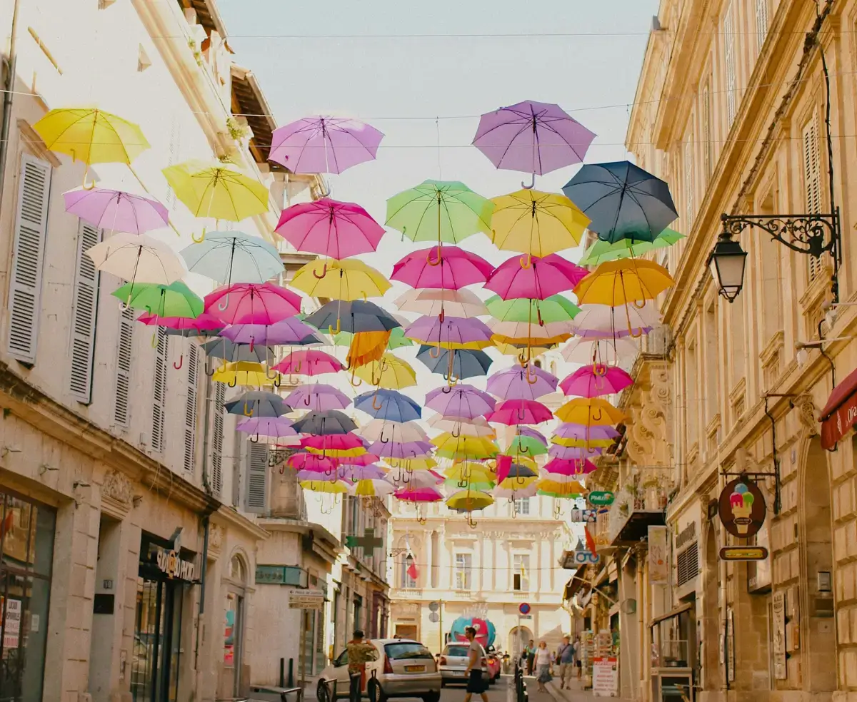 Guarda-chuvas coloridos enfeitando as ruas de Lyon, cercados por arquitetura tradicional da Provence, França.