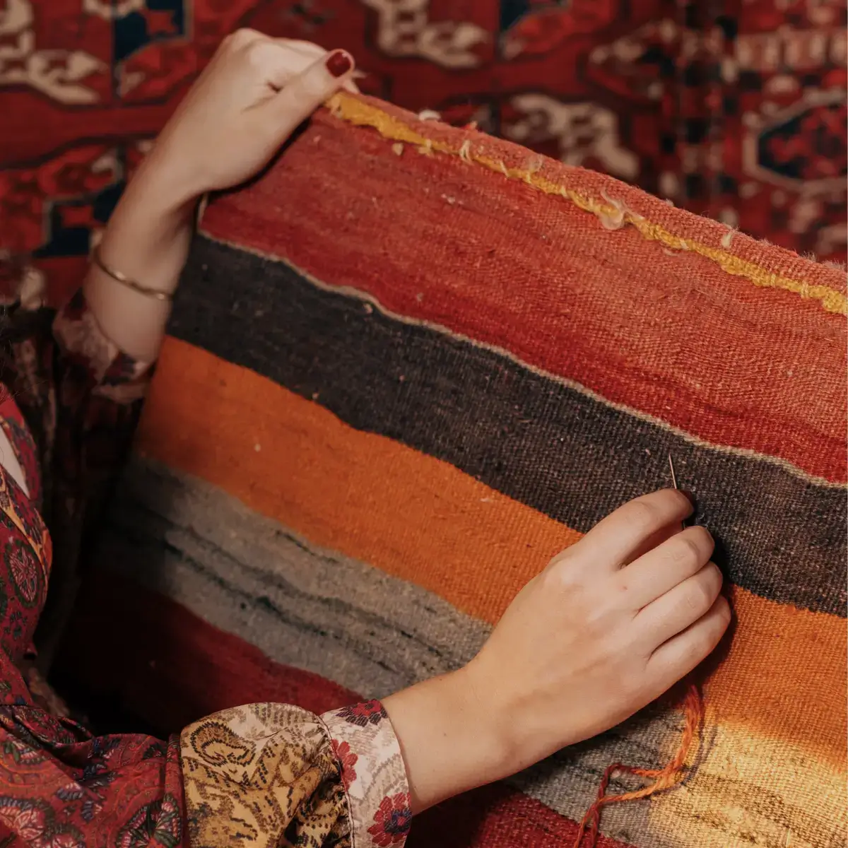 Mão feminina tecendo um tapete turco otomano ou kilim, com cores diversas e vibrantes