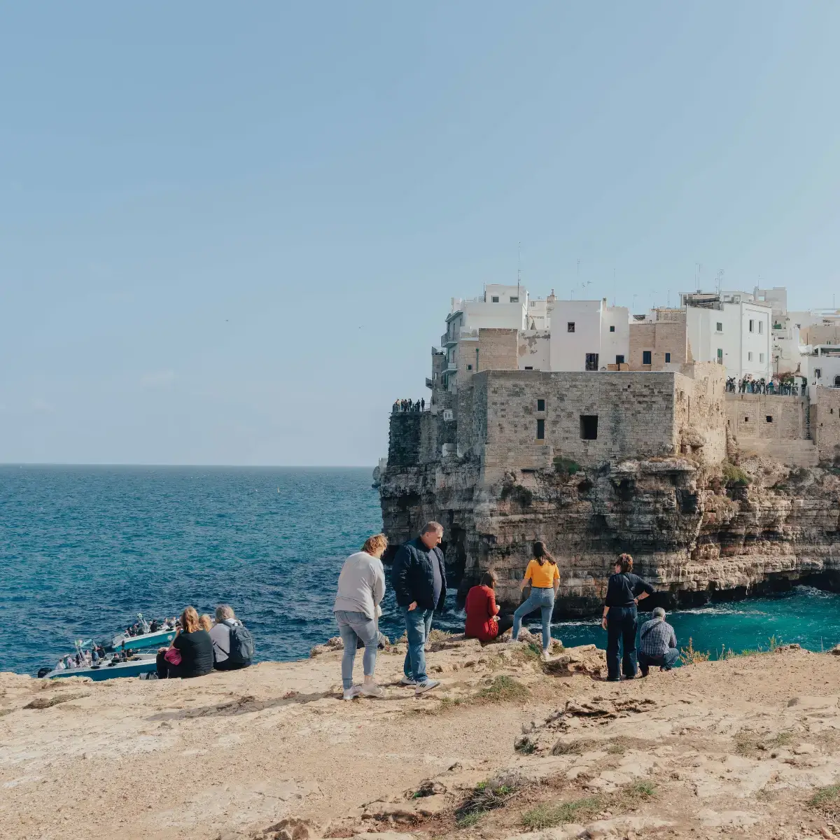 Viajantes maduros caminhando pelo litoral de Bari, na Puglia, com vista do mar Adriático em tons de azul