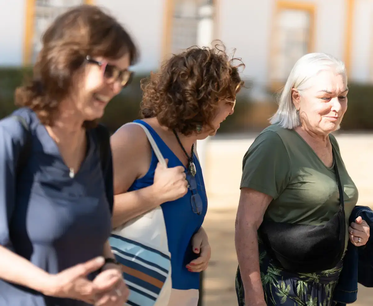Mulheres viajantes da terceira idade conversando e rindo, passeando ao ar livre em uma cidade de Portugal